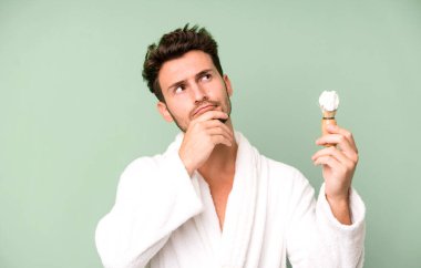 Düşünen, kuşkucu ve kafası karışmış genç bir delikanlı bornoz giyiyor ve tıraş oluyor.