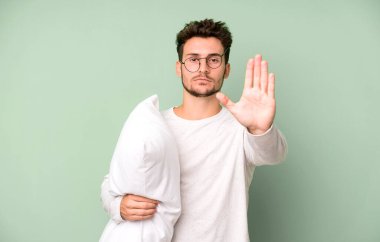 Yakışıklı genç ciddi görünüyor. Avuç içi gösteriyor. Pijama ya da gece elbisesi ve yastık giymekten vazgeçiyor.