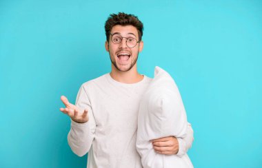 Yakışıklı genç kendini mutlu ve şaşkın hissediyor inanılmaz bir şeye pijama ya da gece elbisesi ve yastık giyiyor.