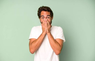 Genç çılgın adam mutlu, neşeli, şanslı ve şaşkın görünüyor. İki eliyle ağzını kapatıyor.