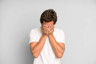 Genç çılgın adam üzgün, hayal kırıklığına uğramış, gergin ve depresif, iki eliyle yüzünü kaplayan, ağlayan