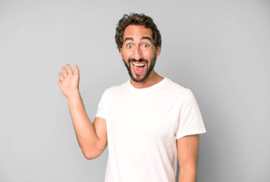 Genç çılgın adam mutlu ve neşeyle gülümsüyor, el sallıyor, seni selamlıyor ve selamlıyor, ya da hoşça kal diyor.