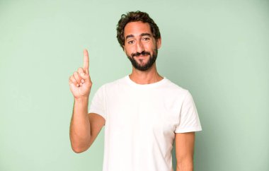 Genç çılgın adam gülümsüyor ve arkadaş canlısı görünüyor. Bir numarayı gösteriyor ya da ilk eli önde, geri sayıyor.