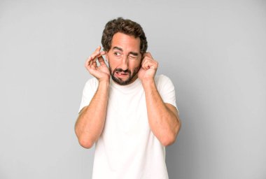 Genç çılgın adam sinirli, stresli ve sinirli görünüyor, iki kulağını da sağır edici bir ses, ses ya da yüksek sesle kapatıyor.