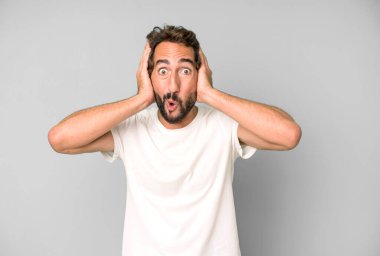 Genç çılgın adam heyecanlı ve şaşırmış görünüyor, ağzı açık, elleri başının üstünde, şanslı bir kazanan gibi hissediyor.