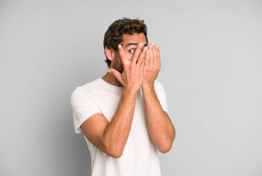 Genç çılgın adam korkmuş ya da utanmış hissediyor. Gözleri yarı kapalı ya da elleri kapalı dikizliyor ya da dikizliyor.