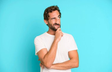 Genç çılgın adam düşünüyor, kuşkulu ve şaşkın hissediyor, farklı seçeneklerle, hangi kararı vereceğini merak ediyor.