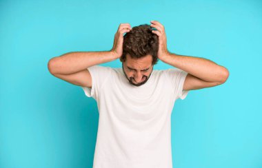 Genç çılgın adam stresli ve hayal kırıklığına uğramış hissediyor, ellerinizi kaldırın, yorgun, mutsuz ve migren ağrısı çekiyor.