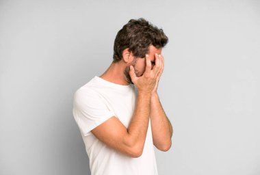 Genç, deli bir adam üzgün, hayal kırıklığına uğramış bakışlarıyla gözleri kapatıyor, ağlıyor, yan gözle bakıyor.