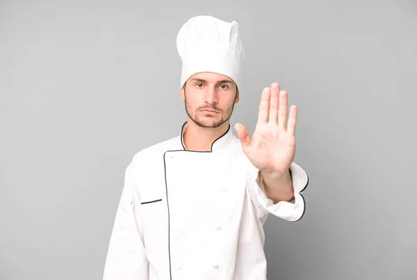 英俊的少年看上去很严肃 露出了张开手掌的停止姿势 厨师概念 — 图库照片