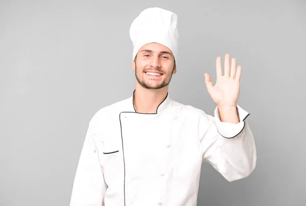 英俊的少年快乐地微笑 挥挥手 欢迎并问候你 厨师概念 — 图库照片
