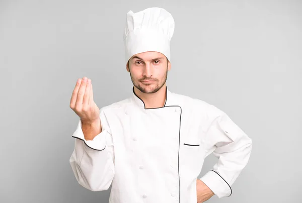 英俊的少年在做花冠或做金钱的手势 让你付钱 厨师概念 — 图库照片