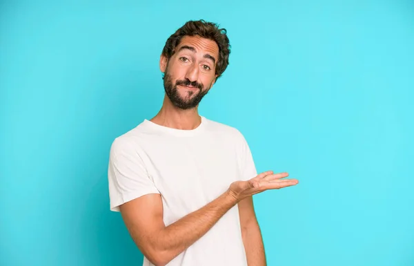 young crazy man smiling cheerfully, feeling happy and showing a concept in copy space with palm of hand