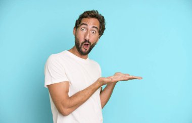 Genç, çılgın, sakallı ve etkileyici bir adam. Yanında fotokopi odası var.