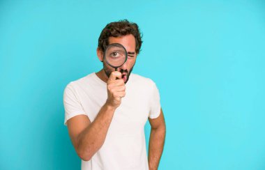 Genç, çılgın, sakallı ve elinde büyüteçle etkileyici bir adam. Ara ya da bul konsepti