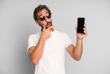 Genç, çılgın, sakallı ve etkileyici bir adam telefonunu kullanıyor.