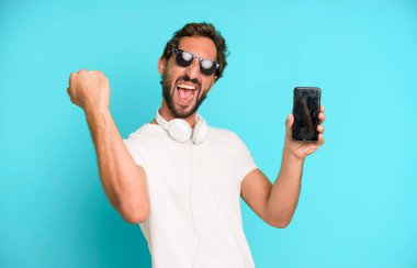 Genç, çılgın, sakallı ve etkileyici bir adam telefonunu kullanıyor.