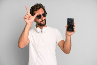 Genç, çılgın, sakallı ve etkileyici bir adam telefonunu kullanıyor.