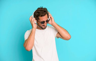 Genç çılgın sakallı ve etkileyici adam müzik dinliyor ve kulaklıkla dans ediyor.