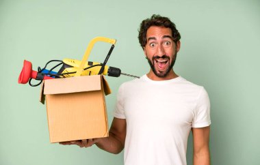 Genç, sakallı ve alet çantalı, etkileyici bir adam. Becerikli adam kavramı