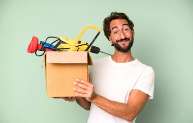 Genç, sakallı ve alet çantalı, etkileyici bir adam. Becerikli adam kavramı