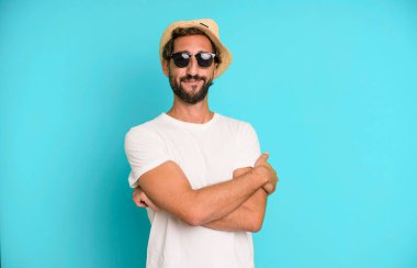 Genç, sakallı, güneş gözlüklü ve şapkalı, etkileyici bir adam. tatil kavramı