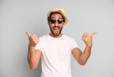 Genç, sakallı, güneş gözlüklü ve şapkalı, etkileyici bir adam. tatil kavramı