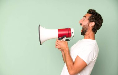 Genç, çılgın, sakallı ve etkileyici bir adam. Bir mesaj vermek için megafon kullanıyor.