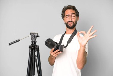 Genç, çılgın, sakallı ve fotoğraf makinesi olan etkileyici bir adam. fotoğrafçı konsepti