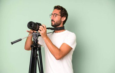 Genç, çılgın, sakallı ve fotoğraf makinesi olan etkileyici bir adam. fotoğrafçı konsepti