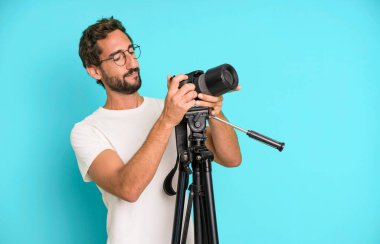 Genç, çılgın, sakallı ve fotoğraf makinesi olan etkileyici bir adam. fotoğrafçı konsepti