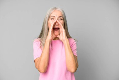Güzel gri saçlı son sınıf öğrencisi mutlu, heyecanlı ve pozitif hisseden, elleri ağızlarının yanında bağıran, bağıran