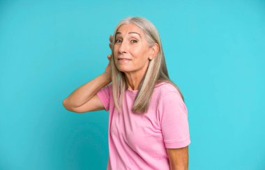 Güzel gri saçlı, kıdemli bir kadın gülümsüyor, tuhaf bir şekilde yan tarafa bakıyor, dedikoduları dinlemeye ya da bir sırrı duymaya çalışıyor.