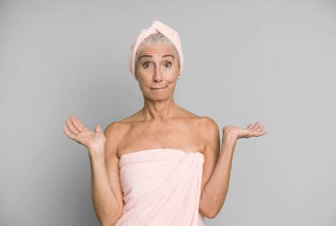 Gri saçlı güzel kadın şaşkın, şaşkın ve şüpheci hissediyor. Bornoz ve havlu giyiyor. güzellik konsepti