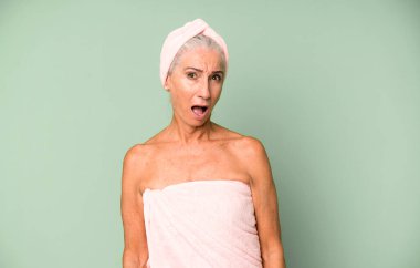 Gri saçlı güzel kadın çok şaşırmış ya da şaşkın görünüyor. Bornoz ve havlu giyiyor. güzellik konsepti