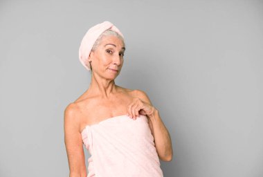 Gri saçlı güzel kadın kibirli, başarılı, pozitif ve gururlu görünüyor. Bornoz ve havlu giyiyor. güzellik konsepti