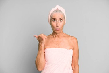 Gri saçlı, güzel bir kadın inançsızlığa şaşırmış görünüyor. Bornoz ve havlu giyiyor. güzellik konsepti