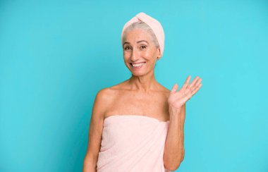 Gri saçlı, güzel bir kadın kendini mutlu hissediyor. Bir çözüm ya da fikir bulduğuna şaşırıyor. Bornoz ve havlu giyiyor. güzellik konsepti