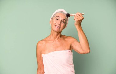 Gri saçlı, son sınıf güzeli, bornoz giyip makyaj yapan güzel bir kadın..