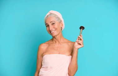 Gri saçlı, son sınıf güzeli, bornoz giyip makyaj yapan güzel bir kadın..