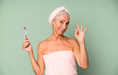 Gri saçlı, son sınıf güzeli, bornoz giyip makyaj yapan güzel bir kadın..