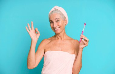 Gri saçlı, son sınıf güzeli, bornoz giyip makyaj yapan güzel bir kadın..