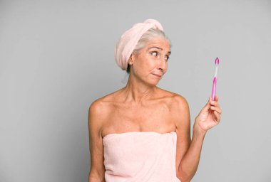 Gri saçlı, son sınıf güzeli, bornoz giyip makyaj yapan güzel bir kadın..