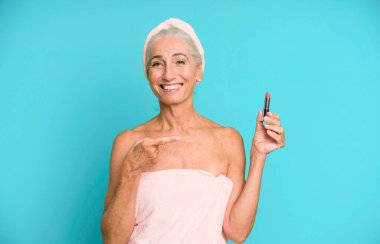 Gri saçlı, son sınıf güzeli, bornoz giyip makyaj yapan güzel bir kadın..