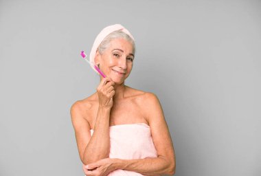 Gri saçlı, son sınıf güzeli, bornoz giyip makyaj yapan güzel bir kadın..