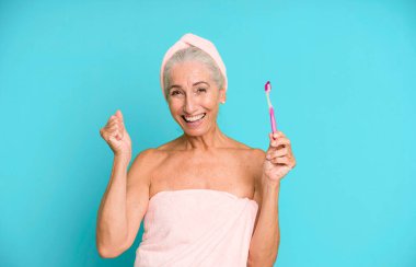 Gri saçlı, son sınıf güzeli, bornoz giyip makyaj yapan güzel bir kadın..