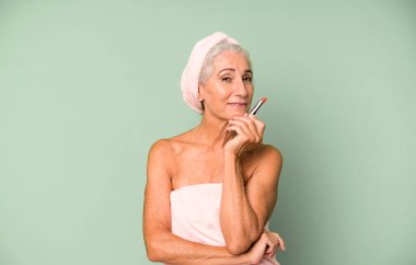 Gri saçlı, son sınıf güzeli, bornoz giyip makyaj yapan güzel bir kadın..