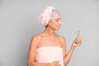 Gri saçlı, son sınıf güzeli, bornoz giyip makyaj yapan güzel bir kadın..