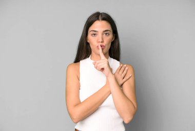 İspanyol güzel kadın ciddi görünüyor ve parmaklarını dudaklarına bastırıp sessizlik ya da sessizlik talep ediyor, sır saklıyor.