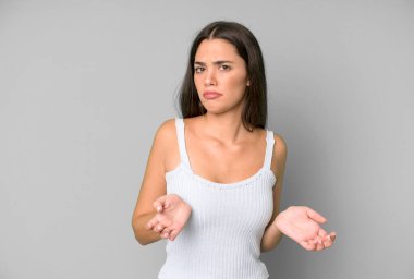 hispanic pretty woman feeling clueless and confused, having no idea, absolutely puzzled with a dumb or foolish look